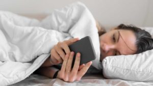 Femme dans son lit sur son téléphone